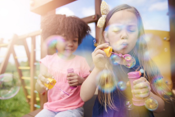 A photo of two children blowing soap bubbles outside.